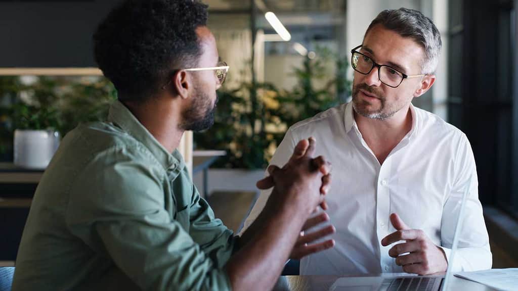 Two men discussing ideas at a table in an office space