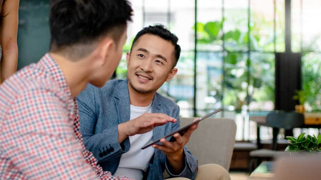 Two people talking while looking at a tablet